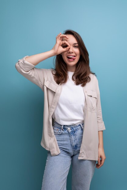 Jolie jeune femme brune bien soignée vêtue d'une chemise et d'un jean se faisant passer pour un modèle