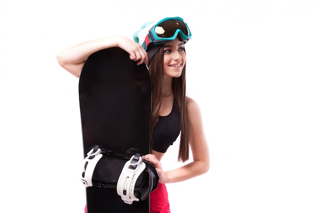 Jolie jeune femme brune en débardeur court noir tenir snowboard