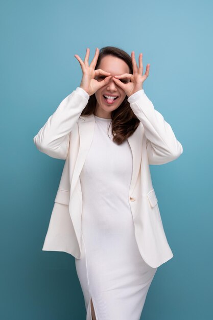 Jolie jeune femme brune européenne dans une robe et une veste avec une grimace