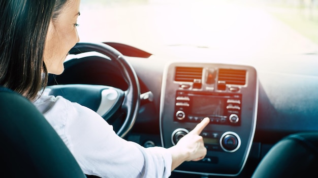 Jolie jeune femme brune heureuse de succès conduit une voiture. Après concession. Travail automatique. Véhicule du futur