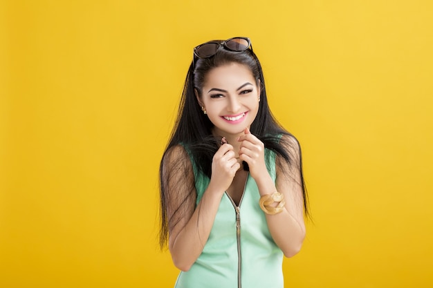 Jolie jeune femme brune en maillot de bain vert sur un jaune. femme souriante dans un body turquoise