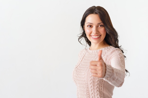 Jolie jeune femme brune avec un sourire rayonnant donnant un pouce vers le haut geste d'approbation et