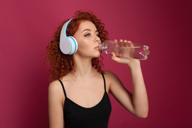 Jolie jeune femme buvant de l&#39;eau minérale pure