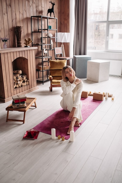 Jolie jeune femme calme méditant se détendre assise sur un tapis naturel dans un intérieur confortable le week-end. Bien-être de la femme