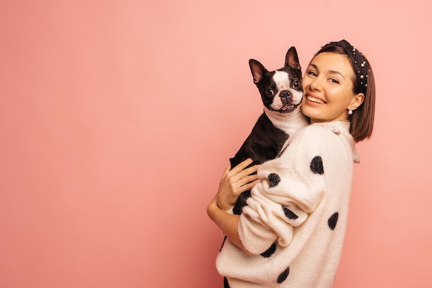 Jolie jeune femme caucasienne pose avec bouledogue français et souriant sur fond rose avec un espace pour le texte Amour entre chien et concept de propriétaire