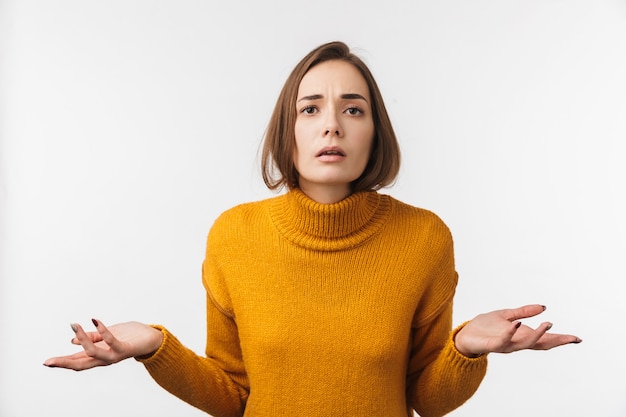 Jolie jeune femme confuse debout isolé sur mur blanc