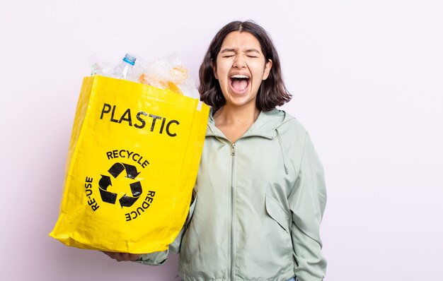 Jolie jeune femme criant agressivement, l'air très en colère. concept de recyclage du plastique