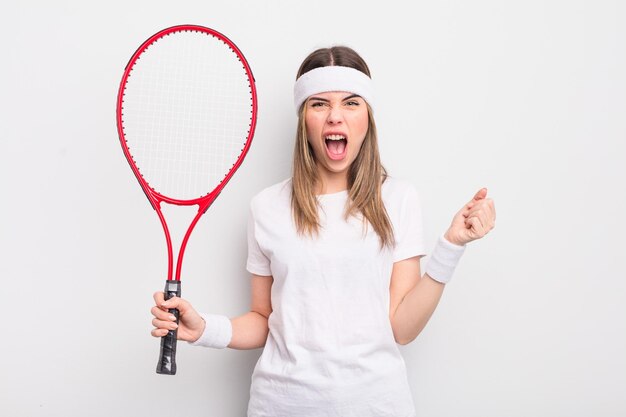 Jolie jeune femme criant agressivement avec un concept de tennis d'expression en colère