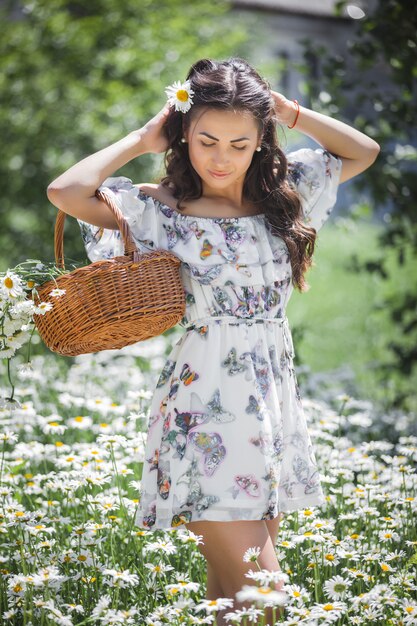 Jolie jeune femme dans le champ de camomille. Belle fille avec des fleurs