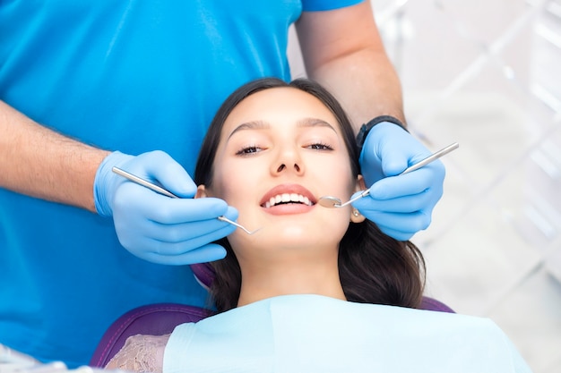 Jolie jeune femme dans une clinique dentaire avec un dentiste masculin