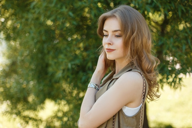 Jolie jeune femme dans un gilet d'été à la mode dans un élégant T-shirt blanc posant à l'extérieur dans le parc