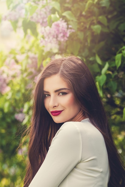 Jolie jeune femme dans un parc de fleurs lilas en fleurs en plein air