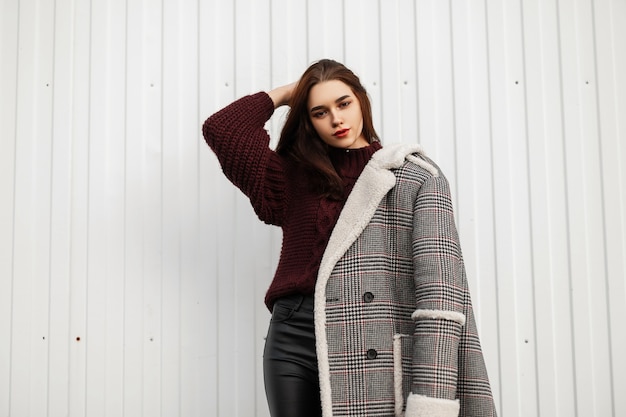 Jolie jeune femme dans une veste longue à carreaux à la mode avec fourrure