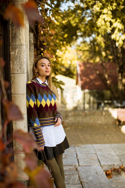 Jolie jeune femme debout à l'extérieur au jour d'automne ensoleillé