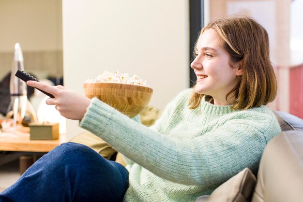 Jolie jeune femme avec un design d'intérieur de maison de bol de pop-corns