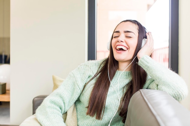 Jolie jeune femme à l'écoute de la musique avec un design d'intérieur de maison d'écouteurs