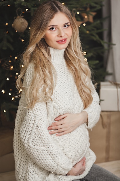 Jolie jeune femme enceinte sur fond de Noël