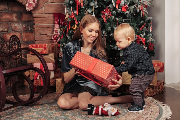 Jolie jeune femme avec un enfant d'un an jouant près de l'arbre de Noël