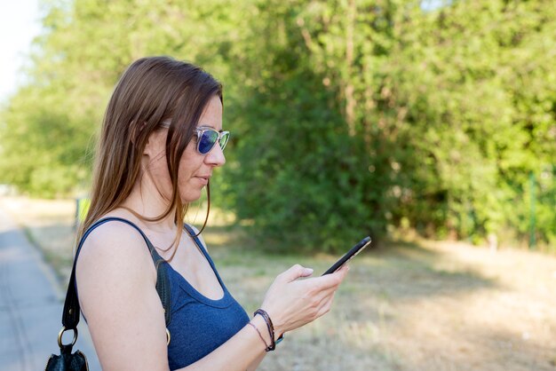 Jolie jeune femme à envoyer des SMS dans la rue