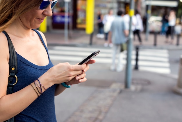 Jolie jeune femme à envoyer des SMS dans la rue