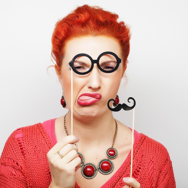 Jolie jeune femme espiègle tenant la moustache et les lunettes sur un bâton. Prêt pour la fête.