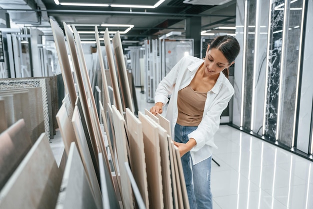 La jolie jeune femme est dans le magasin des marchandises pour la maison