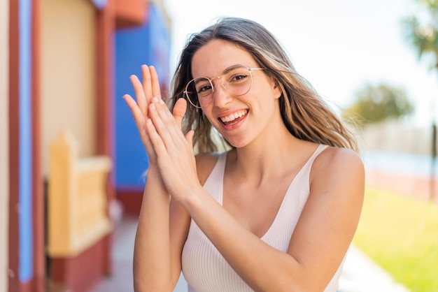 Une jolie jeune femme à l'extérieur avec des lunettes et des applaudissements