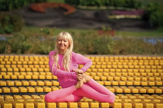 Jolie jeune femme faisant des asanas de yoga dans le parc