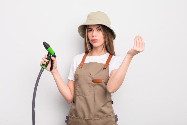 jolie jeune femme faisant un capice ou un geste d'argent, vous disant de payer. concept d'arrosage jardinier