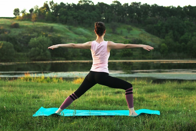 Jolie jeune femme faisant du yoga à l'extérieur.