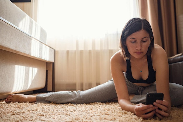 Jolie jeune femme faisant du yoga qui s'étend du yoga en ligne à la maison