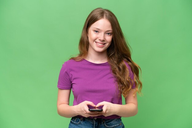 Une jolie jeune femme sur un fond isolé envoie un message avec son téléphone portable
