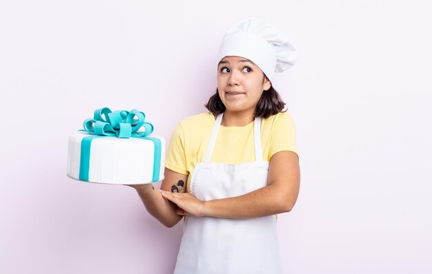 Jolie jeune femme haussant les épaules, se sentant confuse et incertaine. chef cuisinant un gâteau