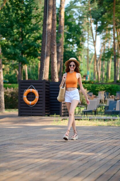 Jolie jeune femme en haut orange et short blanc