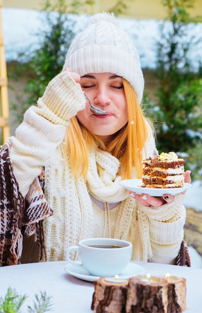 Jolie jeune femme heureuse assise et mangeant un dessert au café