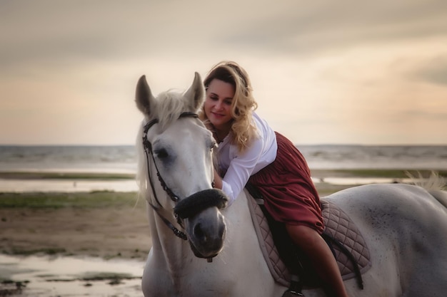 Jolie jeune femme heureuse à cheval sur la plage d'été au bord de la mer