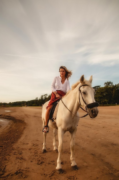 Jolie jeune femme heureuse à cheval sur la plage d'été au bord de la mer