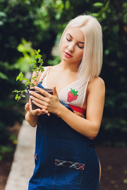 Une jolie jeune femme jardine dans un tablier sans vêtements