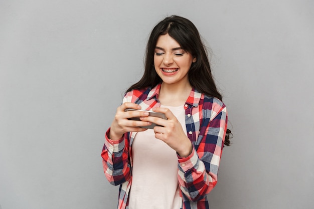 Jolie jeune femme joue à des jeux par téléphone mobile.