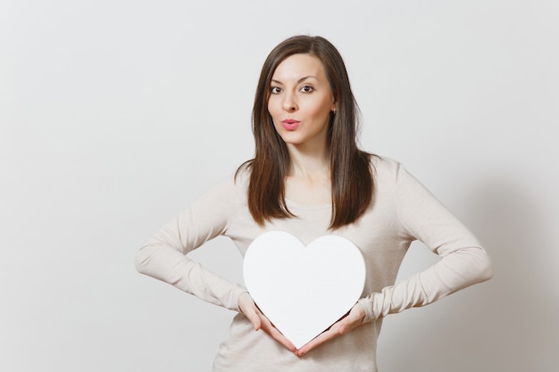 Jolie jeune femme joyeuse tenant un grand coeur blanc dans les mains isolés sur fond blanc. Copiez l'espace pour la publicité. Avec place pour le texte. Concept de la Saint-Valentin ou de la Journée internationale de la femme.