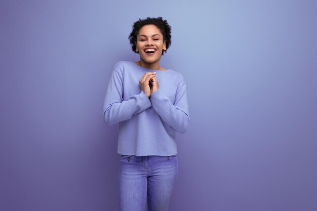 Jolie jeune femme latine aux cheveux afro dans des vêtements de printemps élégants flirtant