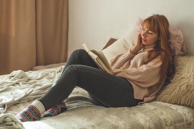 Jolie jeune femme lit un livre à la maison