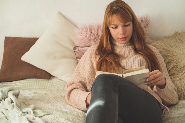 Jolie jeune femme lit un livre à la maison