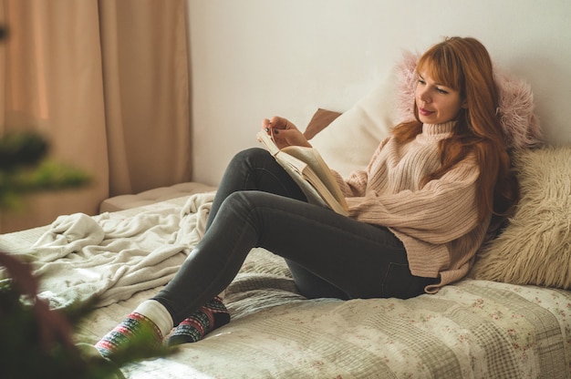 Jolie jeune femme lit un livre à la maison