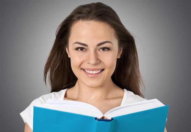 Jolie jeune femme avec livre souriant à la caméra