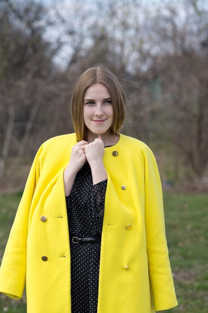 Jolie jeune femme en manteau jaune à l'extérieur