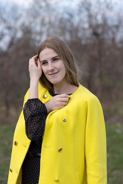 Jolie jeune femme en manteau jaune à l'extérieur