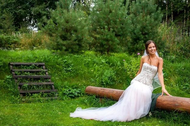 Jolie jeune femme mariée en robe marchant dans la maison de village de campagne à l'extérieur