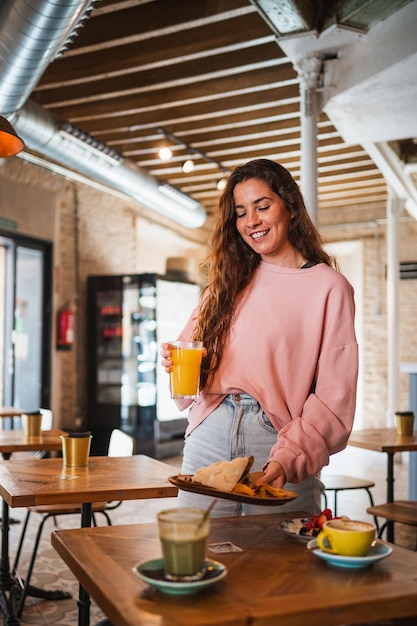 Photo jolie jeune femme mettant sa nourriture sur la table elle prend un brunch dans une cafétéria