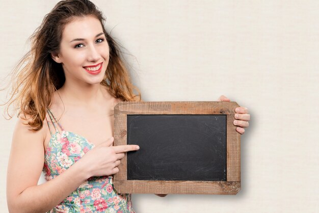 Jolie jeune femme montrant un petit tableau